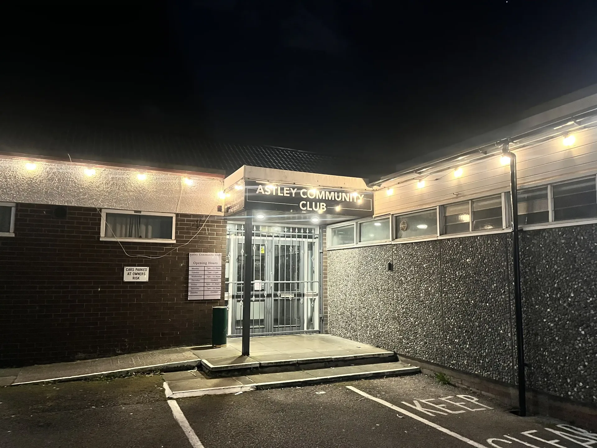 Astley Community Club lit up at night, viewed from Manchester Road